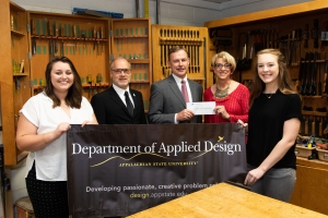 From left to right, interior design senior Hannah Downs, Department of Applied Design Chair Brian Davies, La-Z-Boy’s vice president of human resources, Tim Solesbee, College of Fine and Applied Arts Dean Phyllis Kloda and interior design senior Hailey Estes pose in the department’s wood shop. Kloda and Solesbee are holding the $75,000 check made to the department by the La-Z-Boy Foundation, which will fund L.I.D.A. — the student-designed Lab for Innovating in Design at Appalachian. Photo by Chase Reynolds